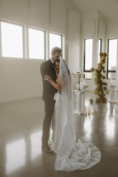 Bride smiles softly as groom holds her in a gentle embrace at elegant Minnesota wedding venue