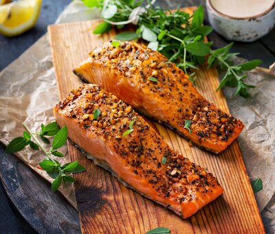 Oven-roasted za’atar salmon fillets on a wooden board with fresh herbs and creamy dressing
