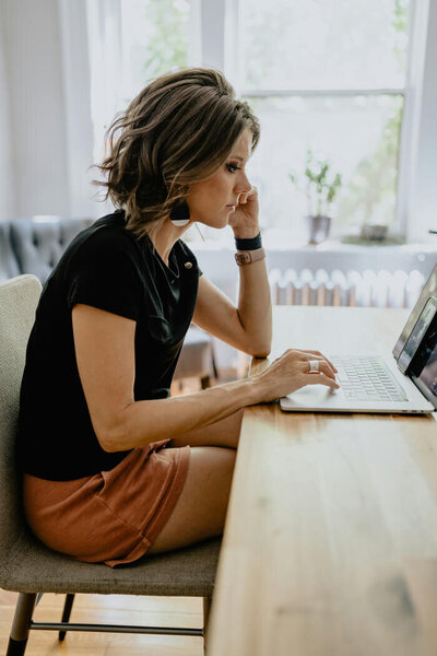 Entrepreneur woman sitting at a desk with a computer and a wooden tray