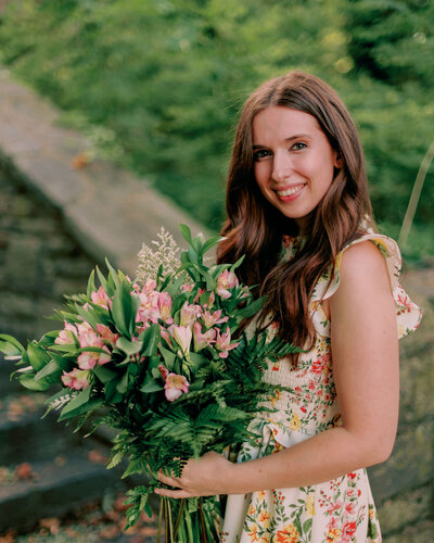 A person holds flowers outdoors.