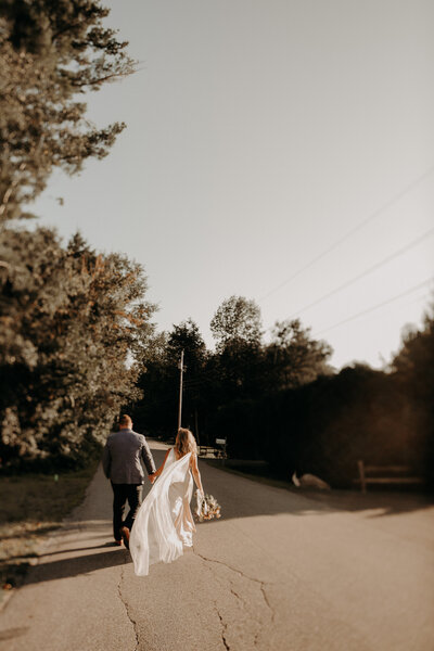 Bride and Groom walking down road holding hands