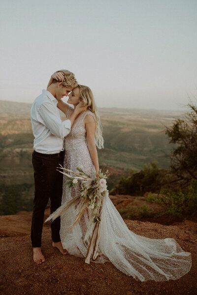 Eloping couple stands together overlooking the Waimea Canyon in Kauai