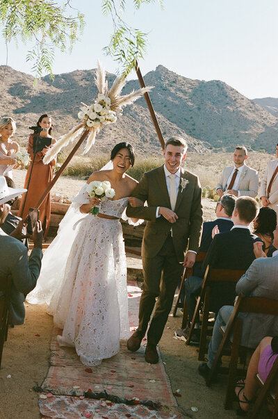 Bride and groom beneath a modern floral arch in desert wedding at Le Chacuel