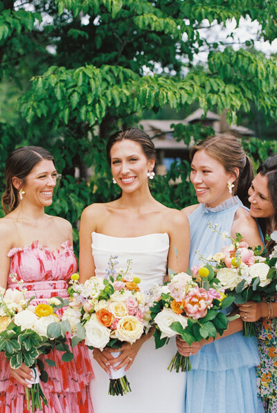 girls in colorful dresses holding colorful flowers smiling at each other
