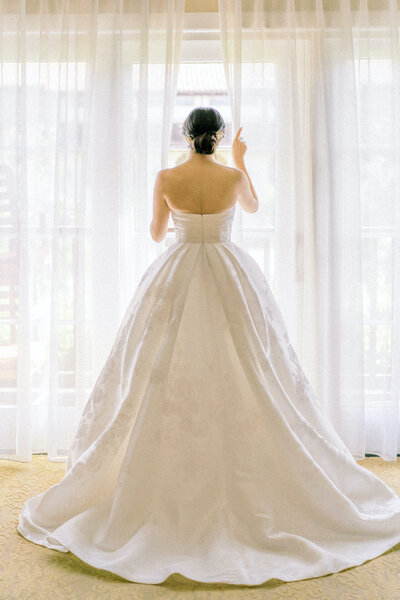 A woman in a wedding dress looking out the window.