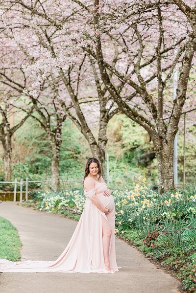 Pregnant mom in pink gown with cherry blossoms in portland park