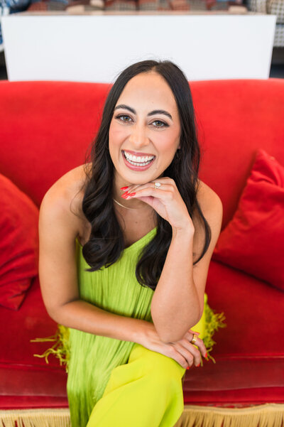 Headshot of Headshot of Dr. Templeton, orthodontist in Nashville, TN, sitting on a red couch in a bright green outfit
