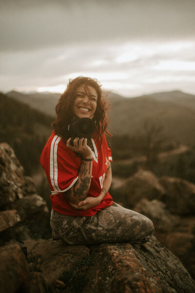 Cinematic editorial portrait in Denver Colorado — queer woman smiling on rocks outdoors, moody vintage film & Super 8 