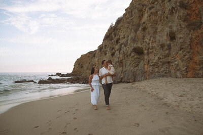 Family walking barefoot along the cliffs at Laguna Beach during a candid photography session.