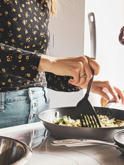 Woman's hands cooking a meal on her stovetop.