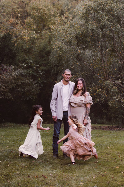 Family Portrait with happy parents standing together with their daughters playing ring around the rosey around them