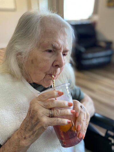 Resident of creekstone senior living enjoying a smoothie a staff member made for her
