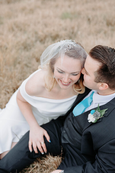 Photo of bride and groom in Texas sitting in a field  together at the Quarry in San Antonio, Texas