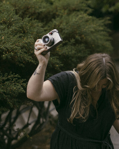 woman holding up her camera in nature