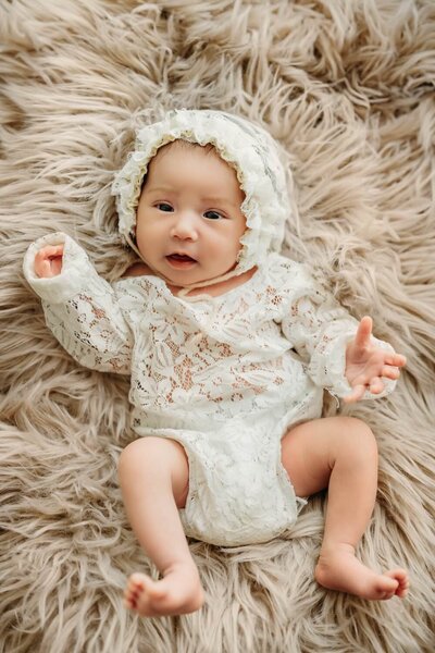 newborn baby girl in a lace outfit and bonnet.