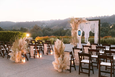 Wedding Ceremony Site with brown wooden chairs, and and altar with white linen backdrop