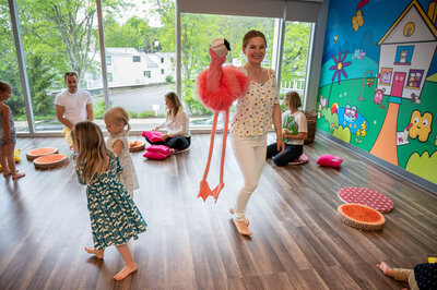 Proprietor of kids music class in Westport, CT,  leading a class while dancing with a flamingo puppet.