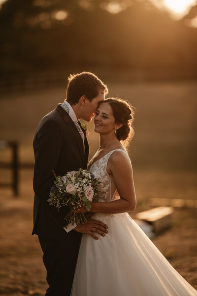 Bride and groom lauging at sun set facing each other in the countryside