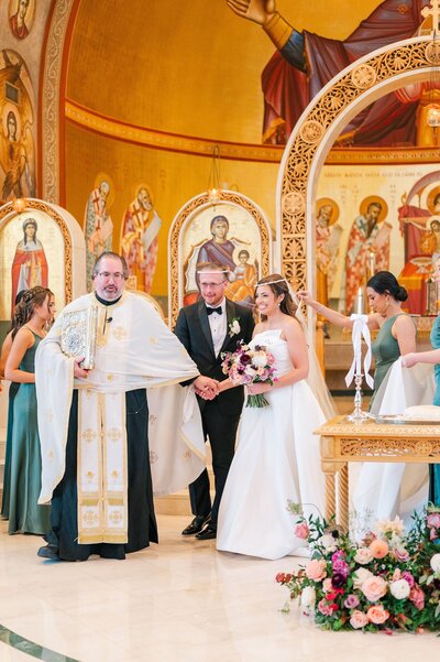 A priest guides a bride and groom through the Dance of Isaiah during their marriage sacrament. 