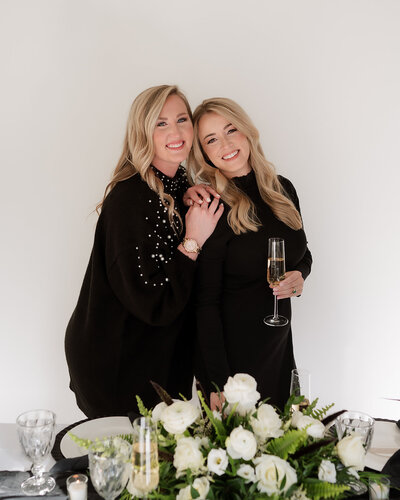 Two females smiling towards camera in front of a decorated table.