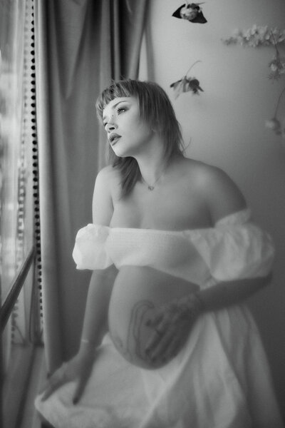 pregnant woman looking out the window during a maternity photoshoot in Colorado