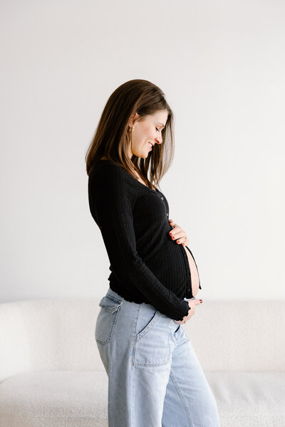 Profile of expecting mother wearing jeans and an unbuttoned cardigan to  show belly during Indianapolis studio maternity photos