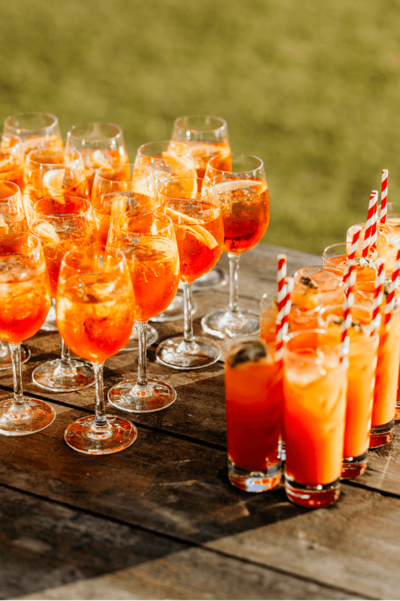 A wooden table with lots of cocktails lines up ready to be served.