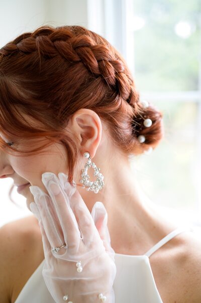 girl grasping earring in bridal attire