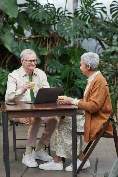 couple sitting at table smiling with a laptop between them