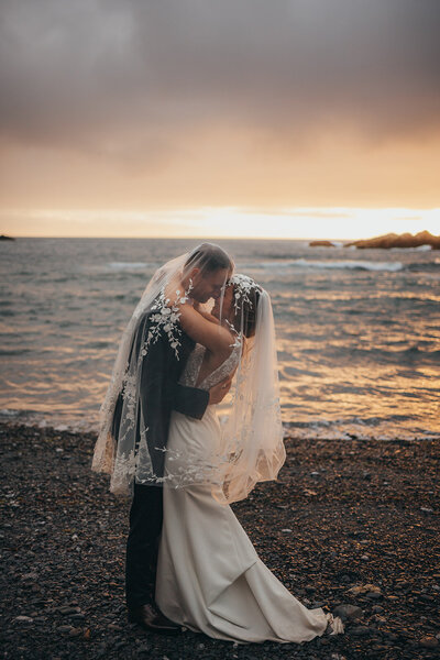 bride and groom embrace on beach