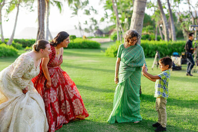 A newlywed couple smiling at a small child at their wedding 