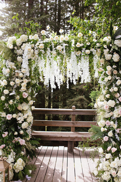 Lucious green wedding arch with hundreds of roses ad white cascading flowers