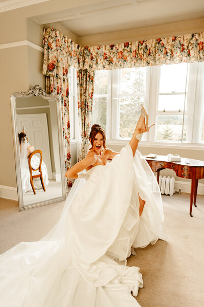 Bride sits with heart shaped gallses on with wine in bathtub
