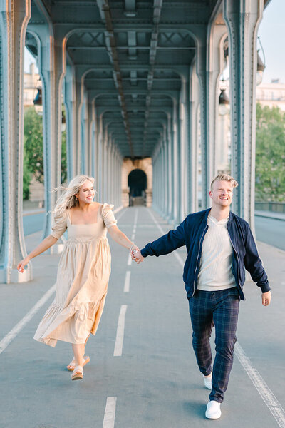 Man and woman holding hands on romantic couple photoshoot in Paris at Bir Hakeim Bridge