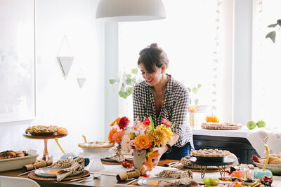 event planner places bouquet of flowers on a curated thanksgiving table scape