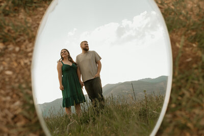 Groom and bride in front of lake with bouquet of flowers in the air