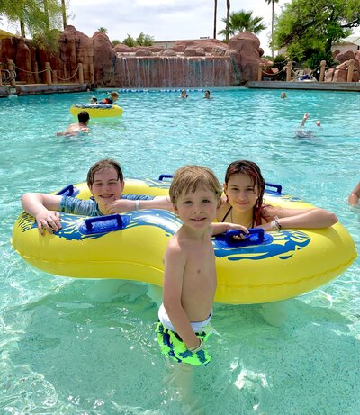 three kids playing in a pool while on vacation