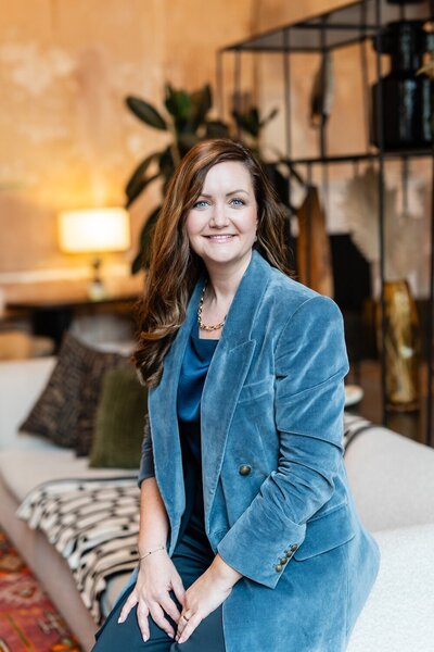 Confidence and career coach Bryony Williams in blue blazer sitting on a sofa