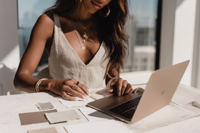 Close-up of a designer arranging neutral fabric swatches and color samples on a table, representing the hands-on creative process during a Studio VIP Day with Kathalyst Design Studio.
