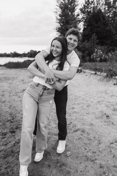 Black and white image of a couple celebrating their engagement on the beaches of a lake in Minnesota