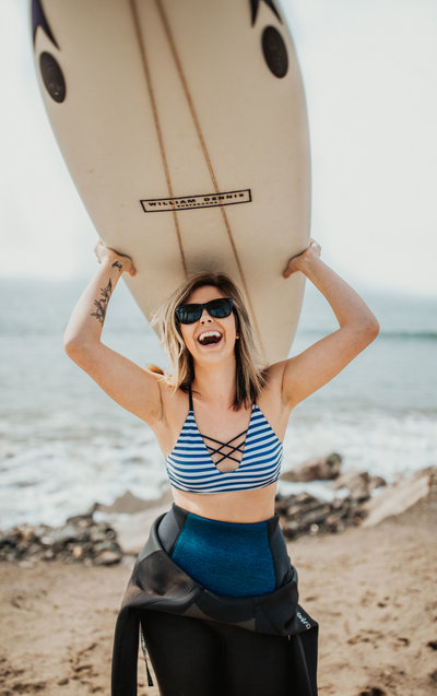 woman holding surf board smiling