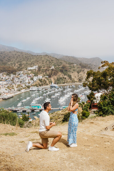 groom down on one knee proposes to surprised bride