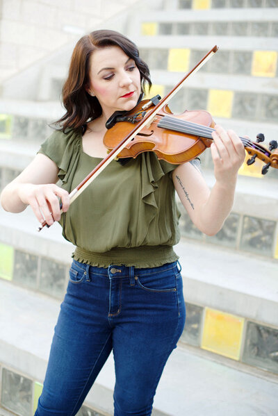 A woman playing a violin outside.