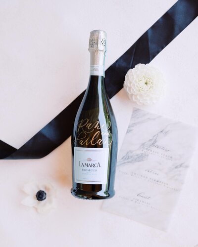 bride and grooms names written in calligraphy on prosecco bottle