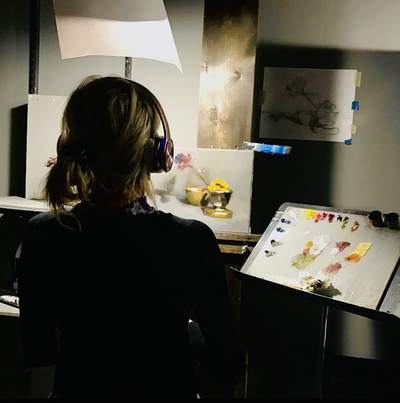 Artist Cam Rose sitting before her palette and still life painting