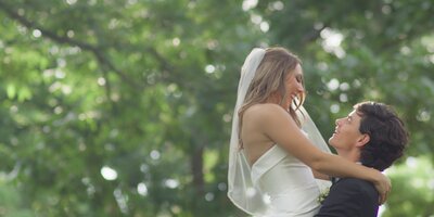 groom holding bride in air smiling at each other