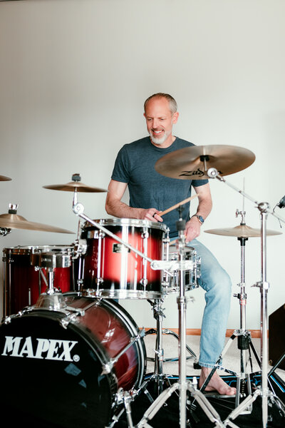 After dating photo showing man playing drums in bright studio, relaxed and expressive image showing personality for dating profile