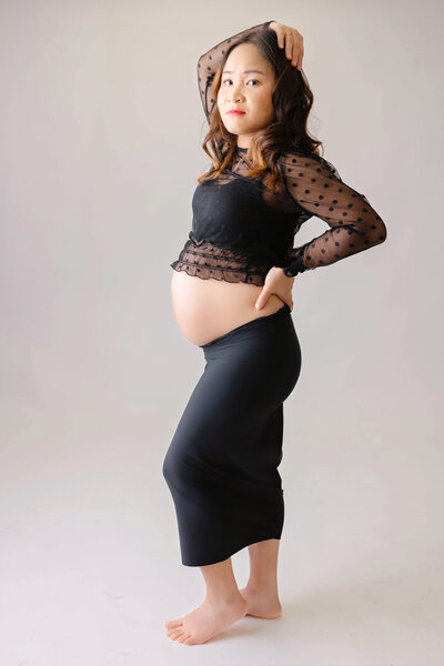 Pregnant mother in a black long skirt and matching top with belly showing. 