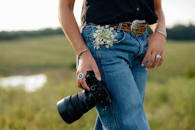 camera held next to body with flowers in the jean pocket