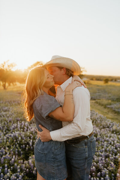 couple kissing in bluebonnet field